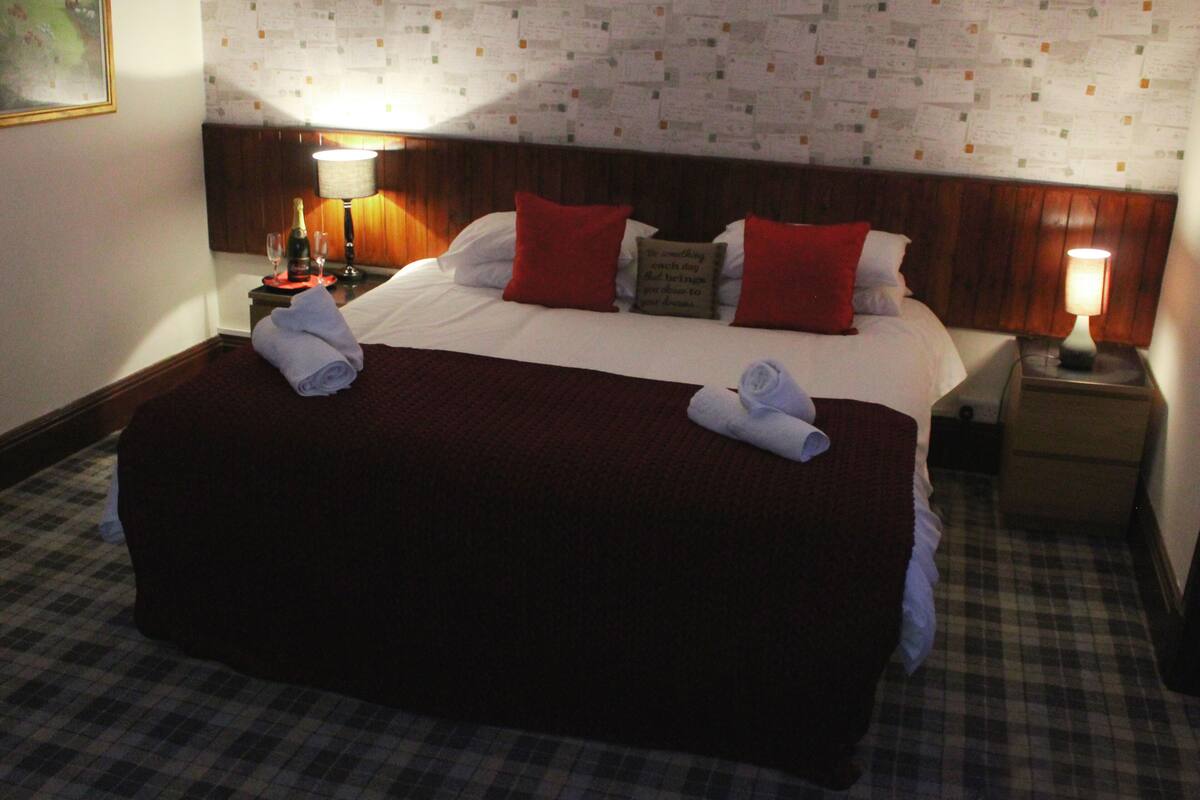 A hotel room with a large bed, two nightstands, a wooden headboard, and a checkered floor.