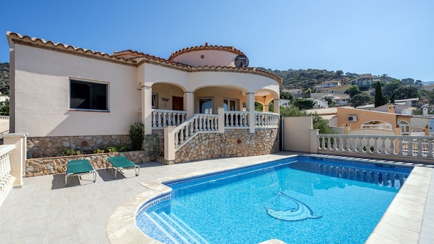 A poolside area with a swimming pool, stone walls, and a balcony with white railings.