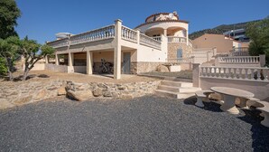 A two-story building with a balcony, stone steps, and a circular structure on the roof.