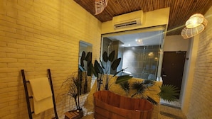 A modern interior with a brick wall, a wooden bench, and a large planter with tropical plants. - Language Exchange Hotel 3 (Ho Chi Minh City)