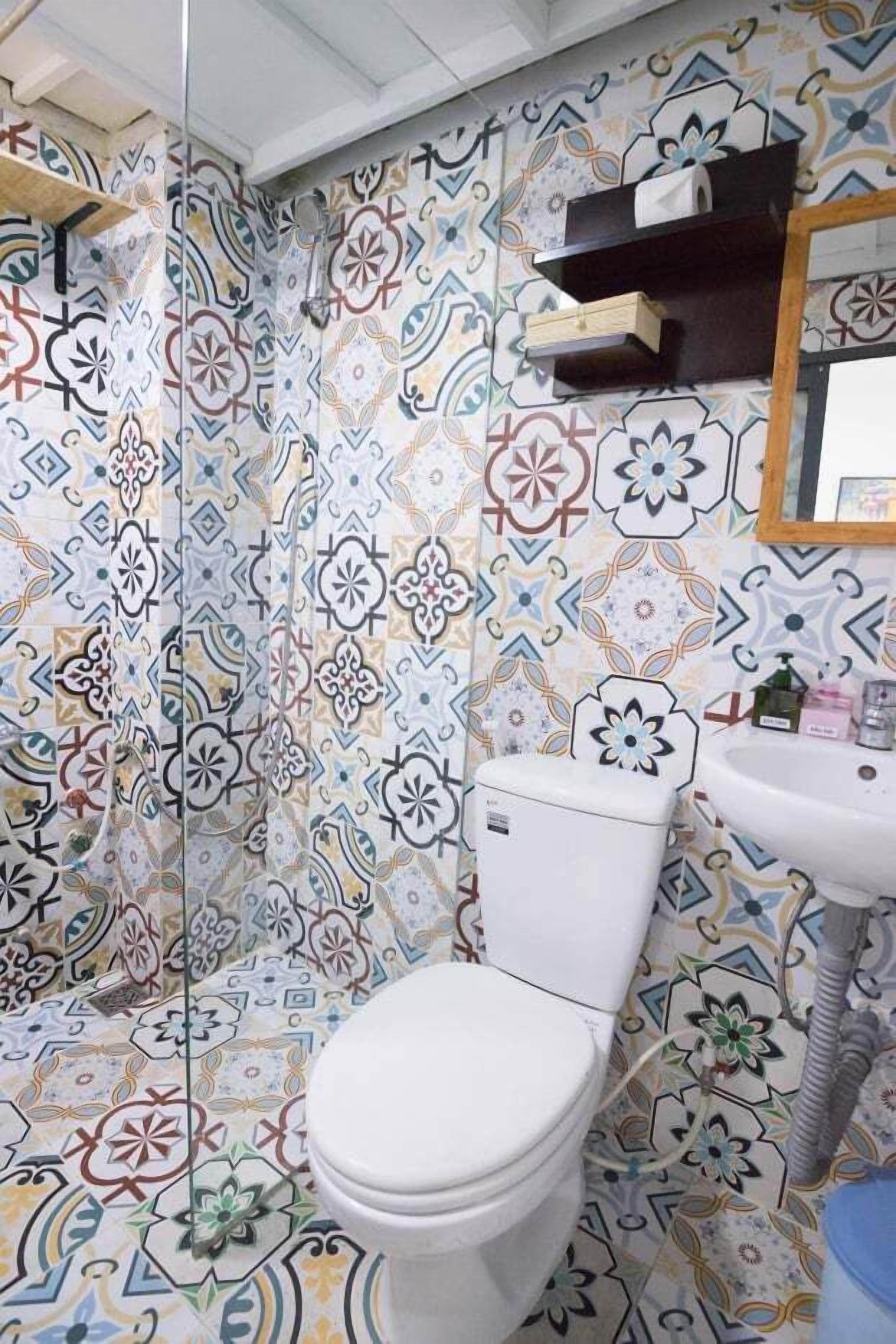 A bathroom with a patterned tile wall, a white toilet, a sink, and a mirror above the sink.