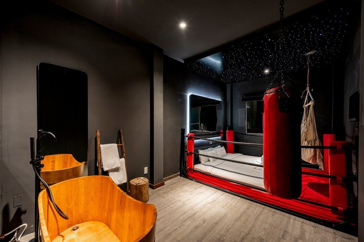 A compact room with a boxing ring, a wooden chair, a small stool, and a mirror on the wall.