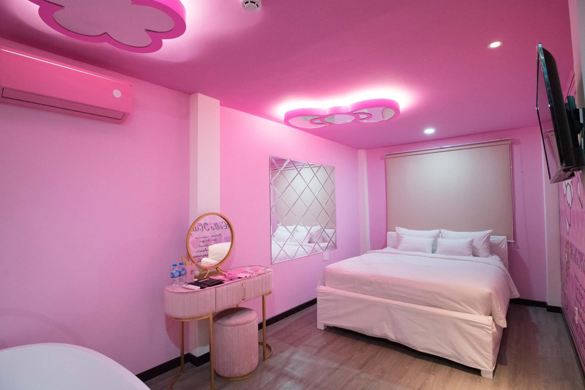 A pink-themed bedroom with a bed, vanity, and a decorative mirror.