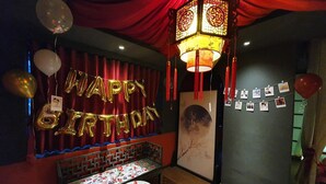 A room with a red curtain, a 'Happy Birthday' balloon decoration, a table with photos, and a traditional lantern. - Language Exchange Hotel 3 (Ho Chi Minh City)