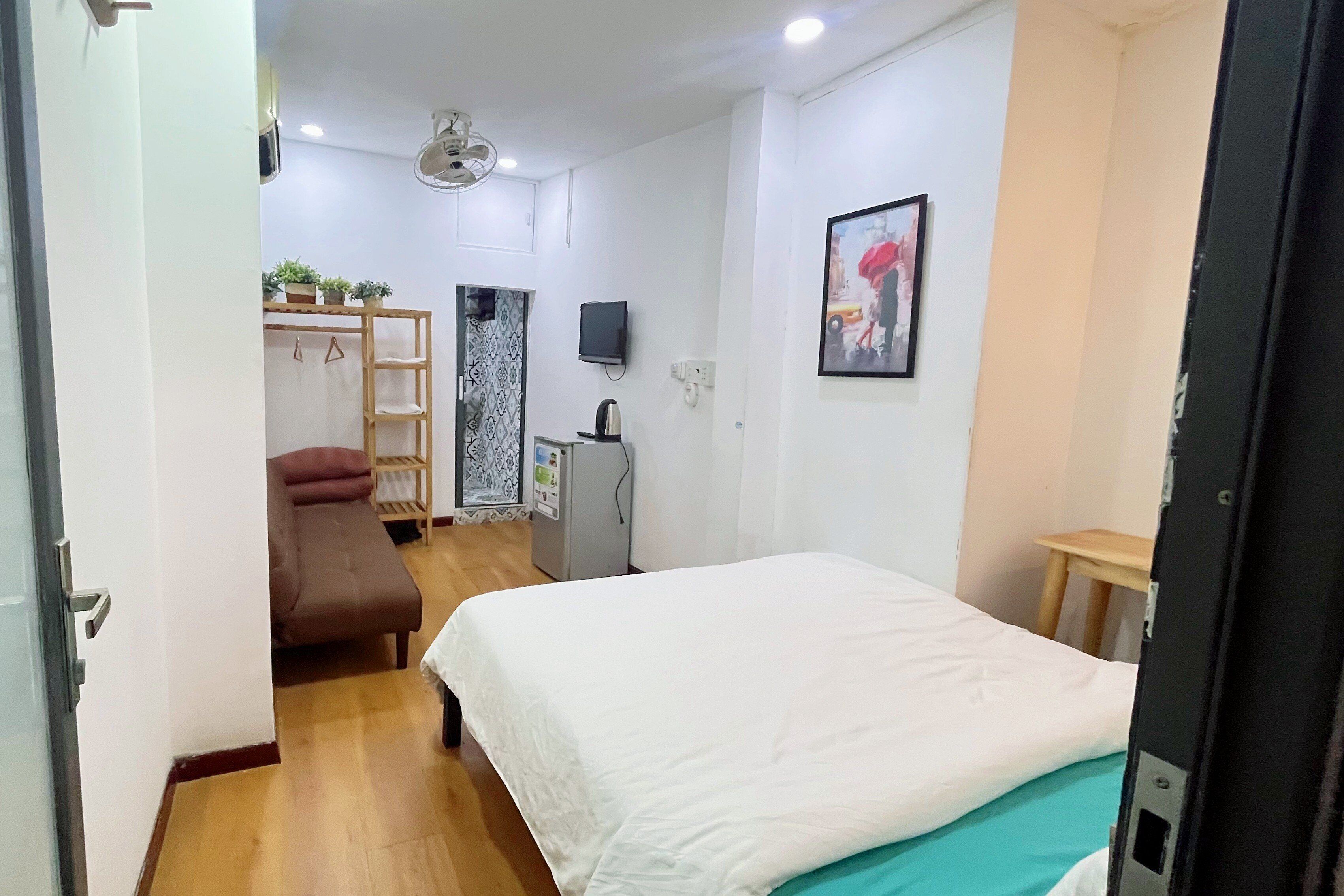 A bedroom with a bed, a desk, a chair, a TV, and a wardrobe.