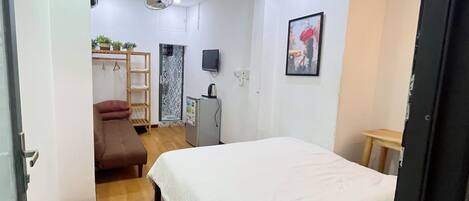 A bedroom with a bed, a desk, a chair, a TV, and a wardrobe.
