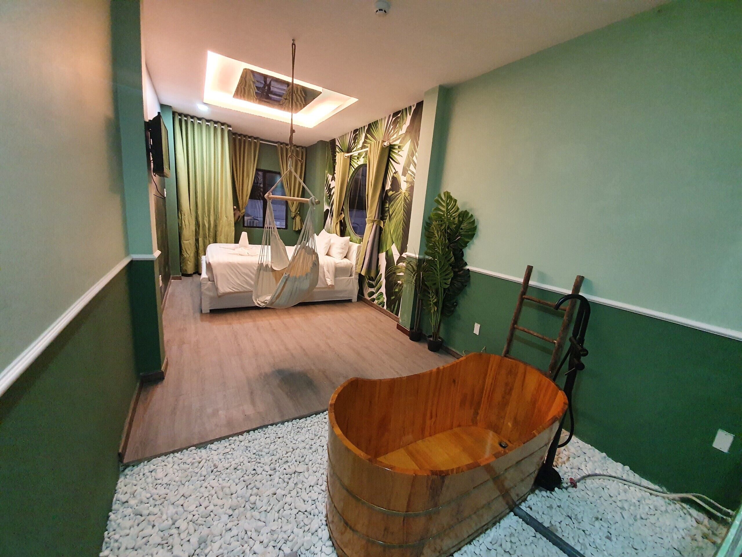 Une pièce comprenant un lit, un fauteuil suspendu, une baignoire en bois et des plantes en pot.