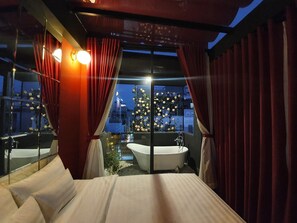A bedroom with a large bed, a bathtub, and a window with curtains. - Language Exchange Hotel 3 (Ho Chi Minh City)