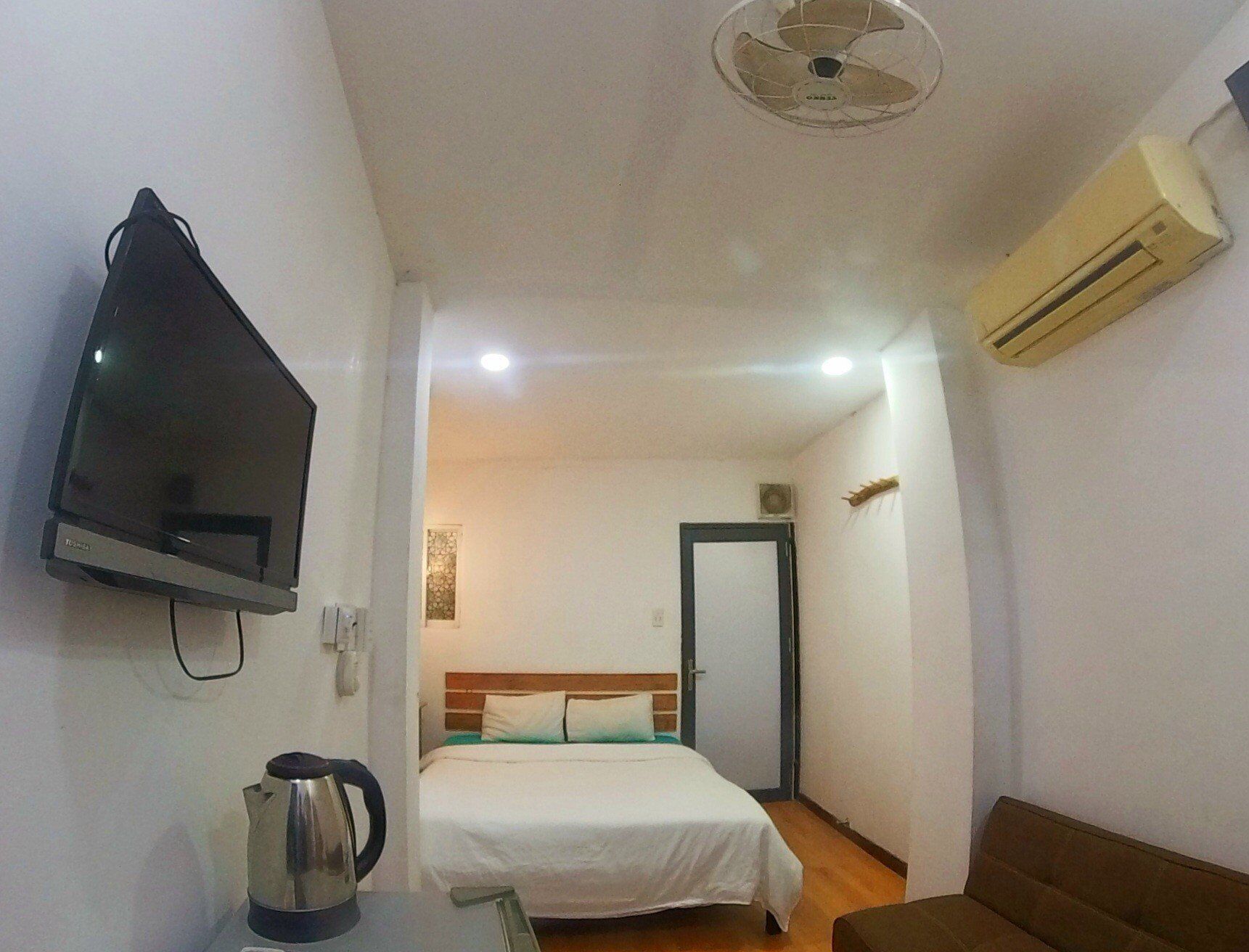 Una camera d'albergo compatta con un letto, una televisione, una macchina per caffè e un condizionatore.