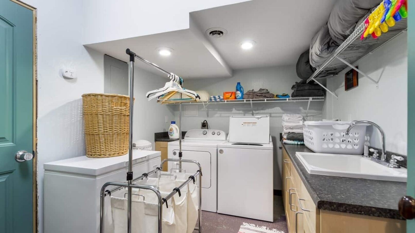 Une cuisine de taille réduite équipée d’un lave-linge, d’un sèche-linge et d’un évier.