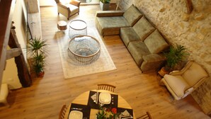 A spacious living area with a wooden floor, a round coffee table, a sofa, and a dining table set for four. - Eguen Goiko (Ispaster)