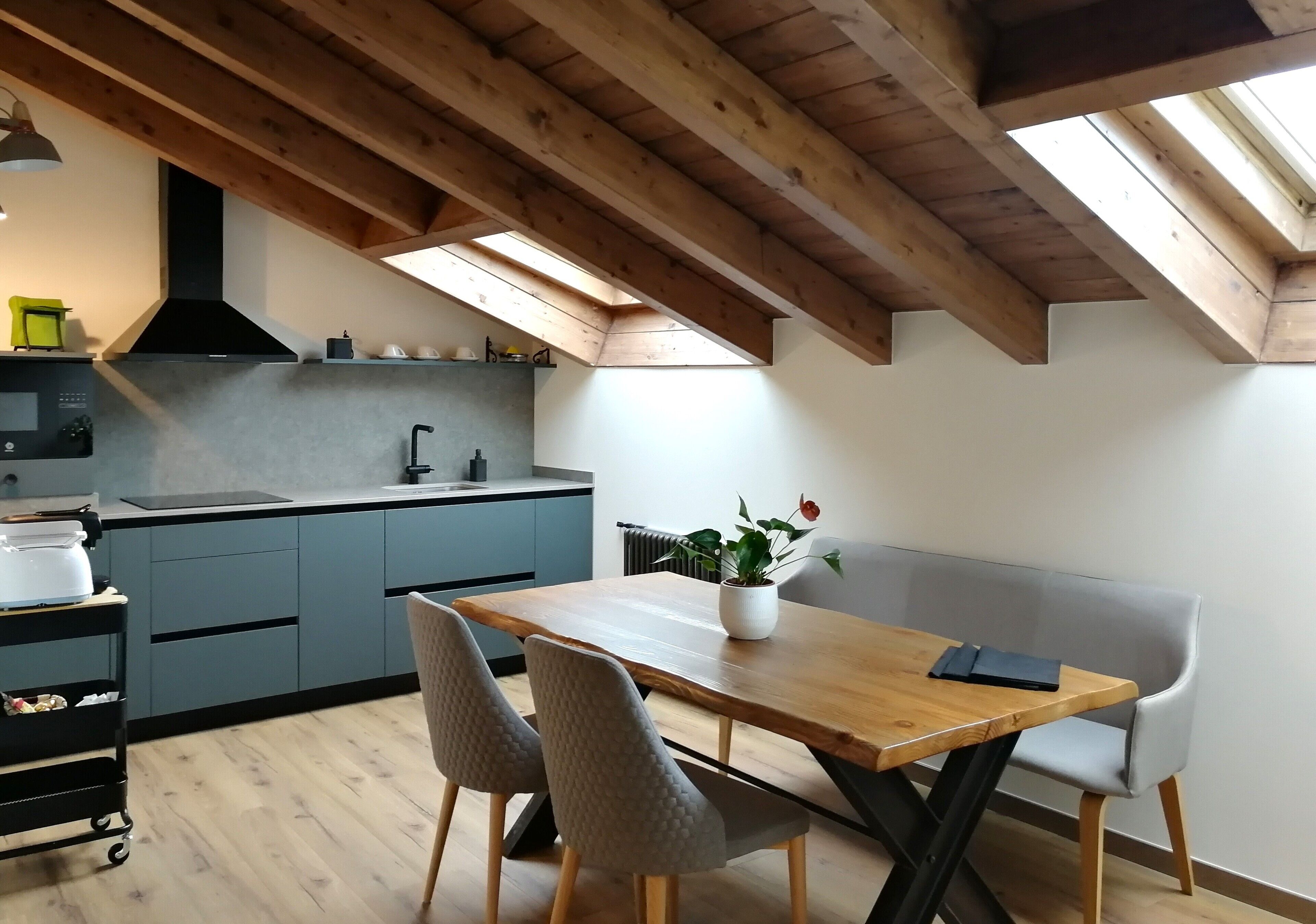 A modern kitchen with a wooden ceiling, skylight, and a dining area with a table and chairs.