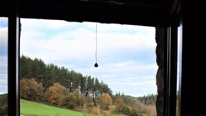 A room with a large window offering a view of a grassy field and trees. - Eguen Goiko (Ispaster)