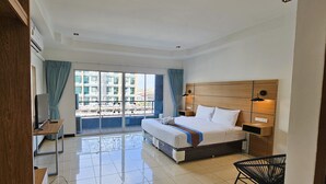Ein Hotelzimmer mit Bett, Nachttischen, einem Sessel und Blick nach außen.