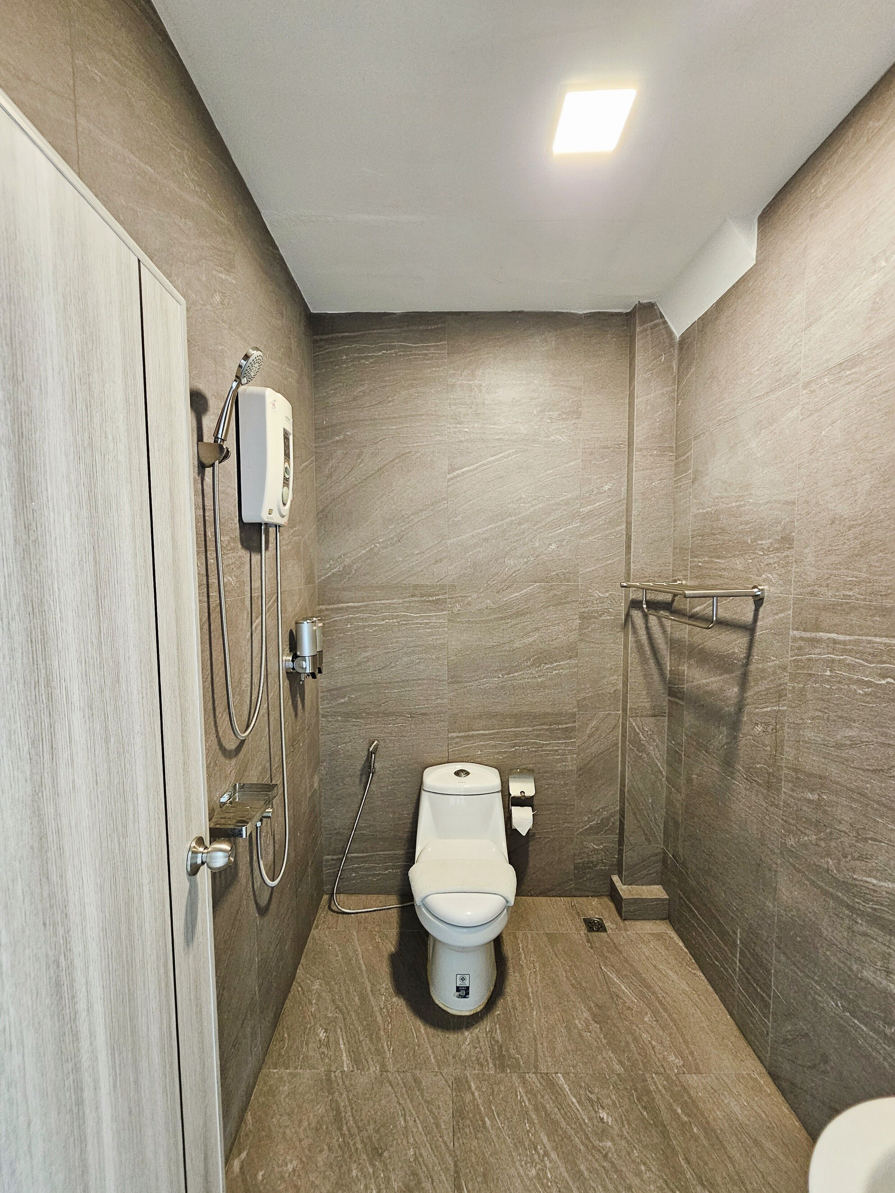 A modern bathroom with a toilet, shower, and hand dryer.