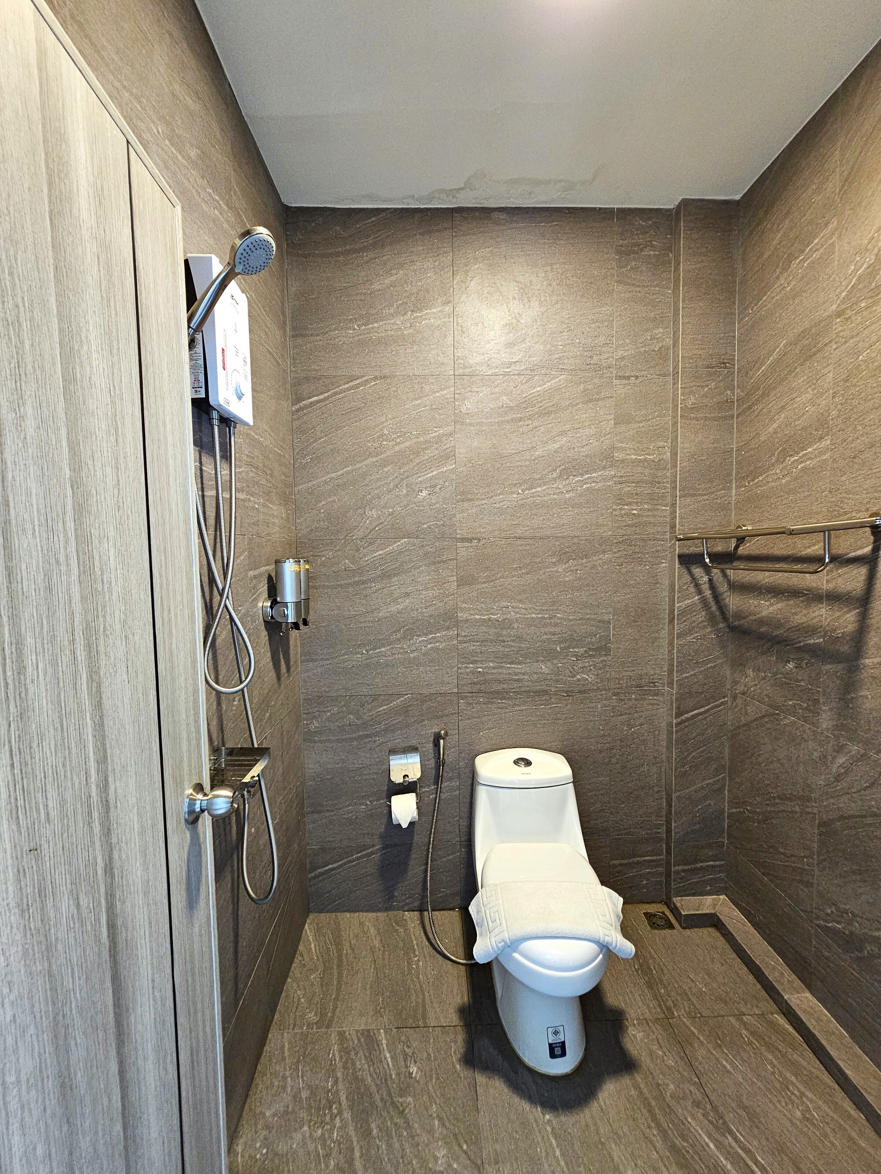 Une salle de bain moderne équipée de toilettes, d’une douche et d’un porte-serviettes.