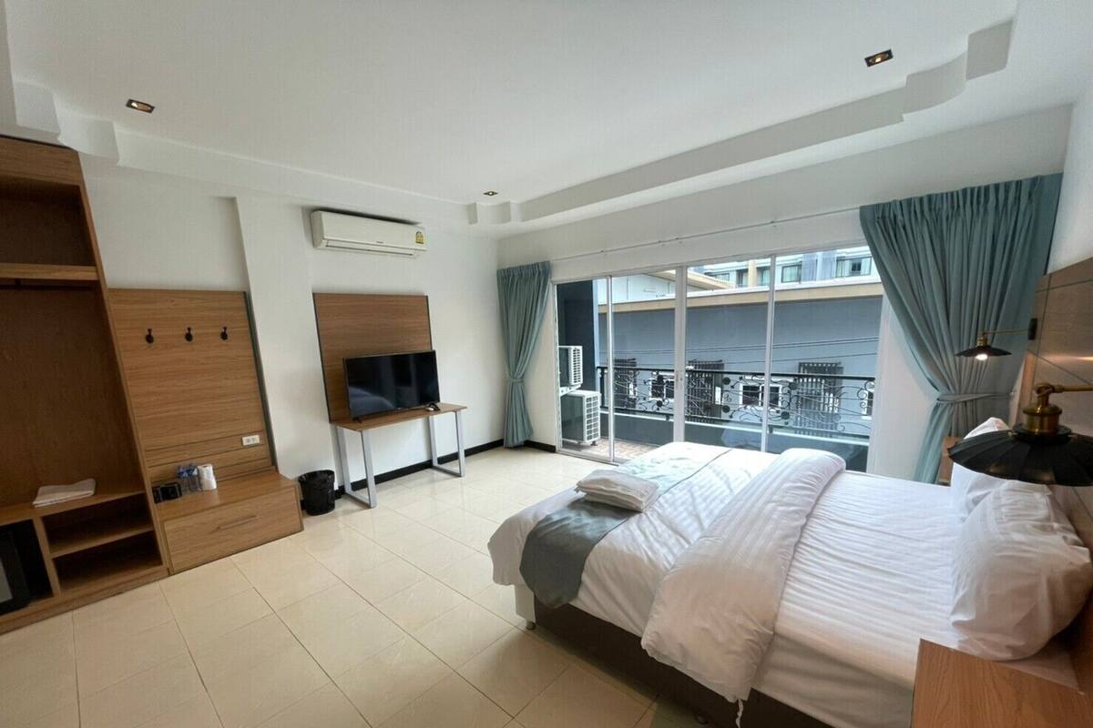 A hotel room with a bed, a TV, a wardrobe, and a balcony with a view.
