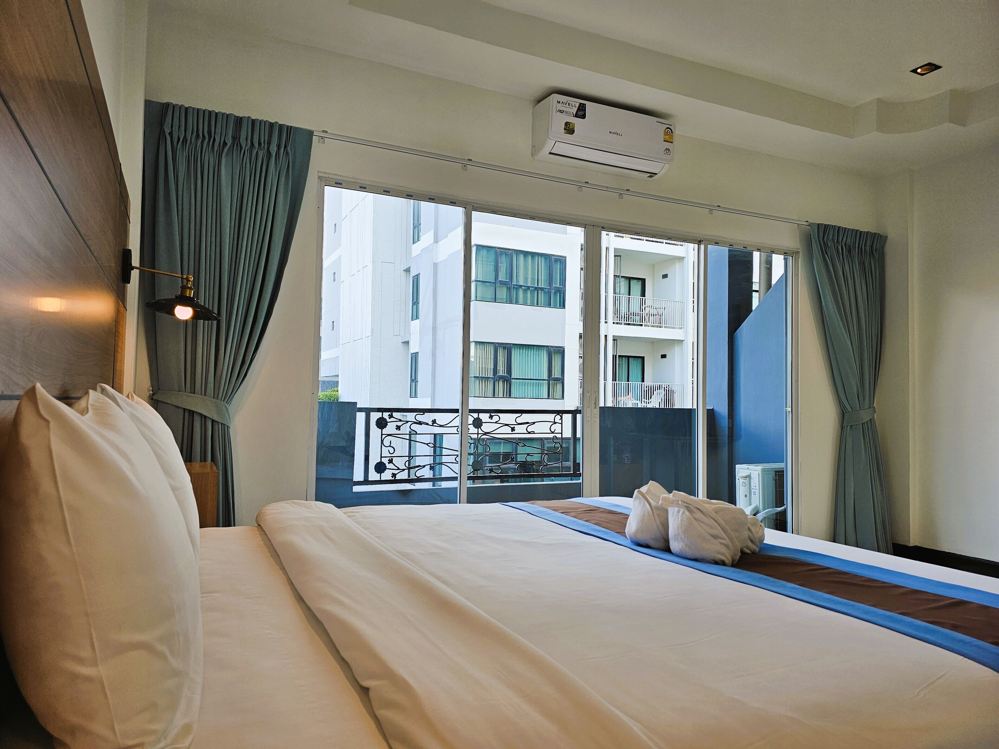 Ein Hotelzimmer mit Bett, Vorhängen, einem Fenster und einer Klimaanlage.