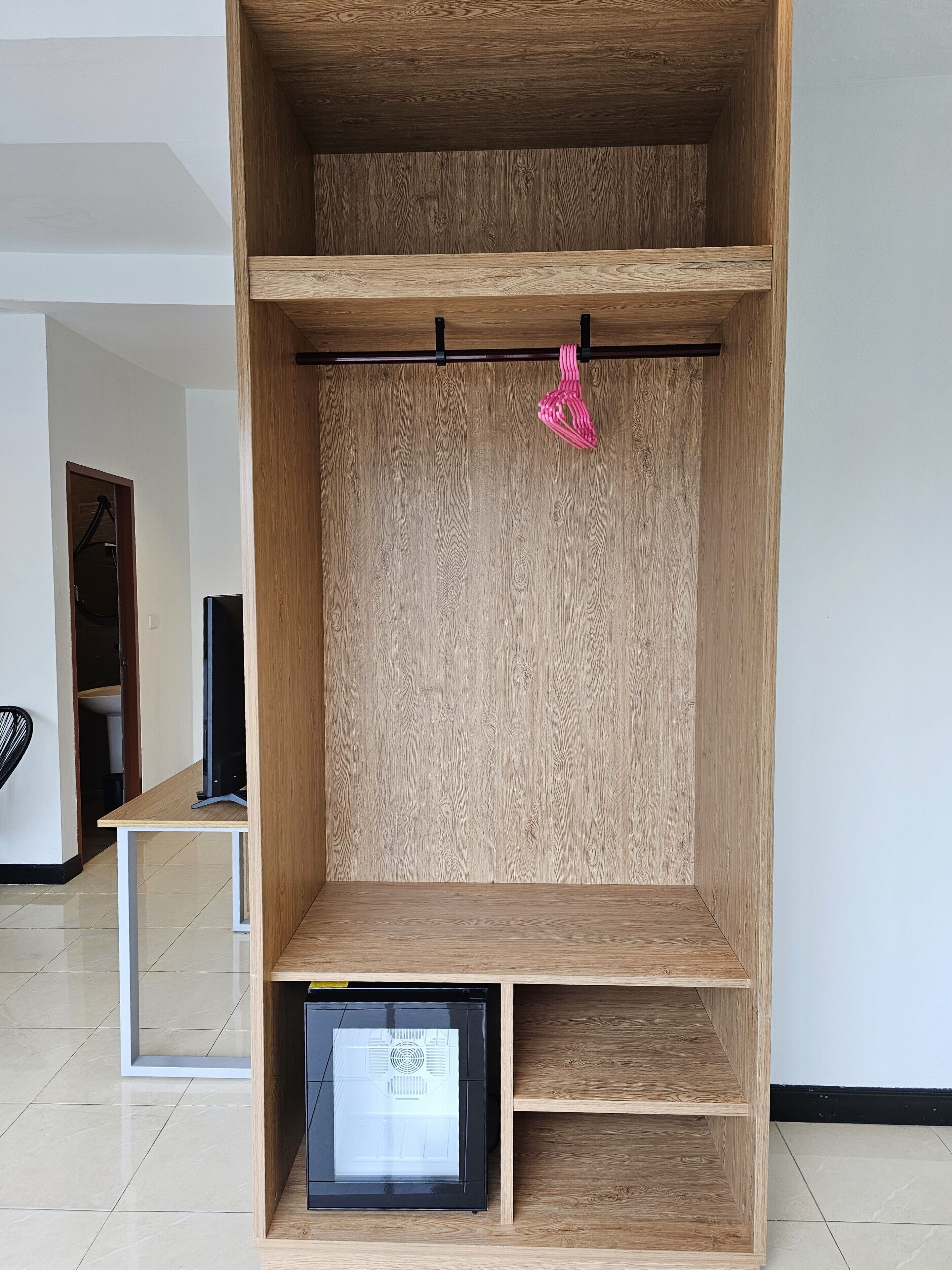 Una habitación con un armario de madera, una mesita pequeña y un marco negro para cuadros.