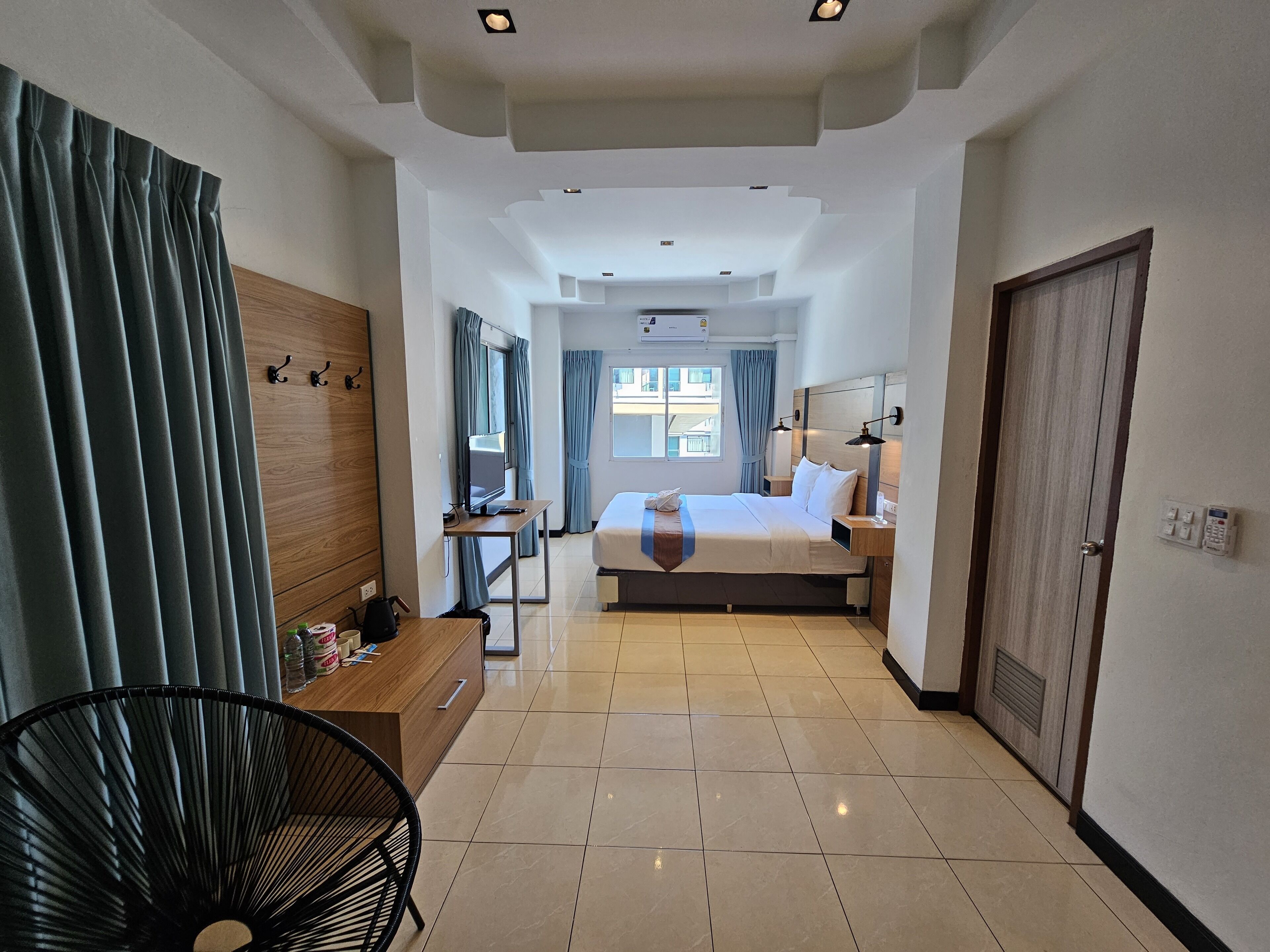 A hotel room with a bed, a desk, a chair, and a TV.