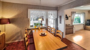 Un coin repas avec une table en bois, des bancs rembourrés et une plante en pot.