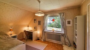 Une chambre confortable avec un lit, un bureau et un radiateur près d’une fenêtre ornée de rideaux.