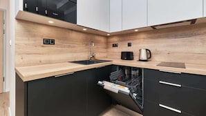 Una cocina moderna con lavavajillas, hervidor y microondas.