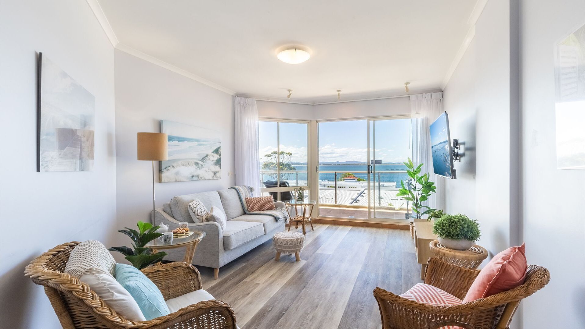 Una sala de estar moderna con sofá, sillas, una mesa de centro y un balcón con vistas al mar.