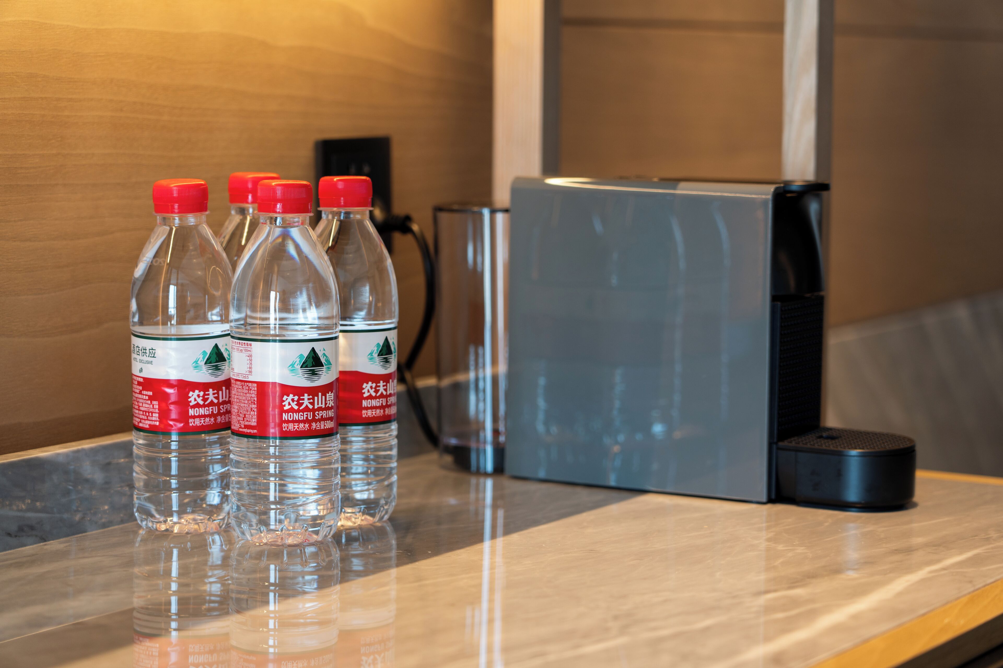 A table with four water bottles and a small black device, possibly a speaker, in a hotel setting.