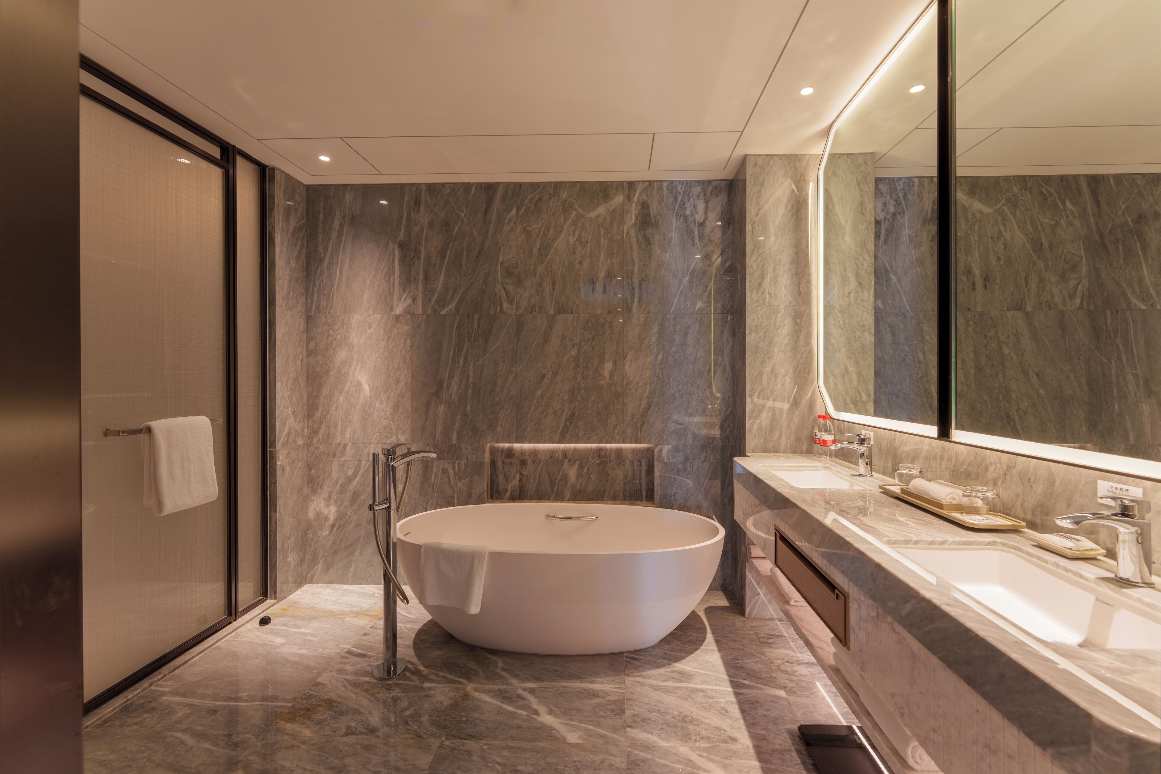 A modern bathroom with a freestanding bathtub, a large mirror, and a vanity with a sink.