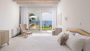 A bedroom with a large bed, a chair, a view of the sea through a glass door, and a view of the sky. - Nisos Green Villa, Private Beach & Pool (Corfu)