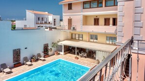 A multi-story building with a swimming pool, outdoor seating, and a covered patio area. - Residence con piscina a 300 mt dal mare (Santa Teresa di Gallura)