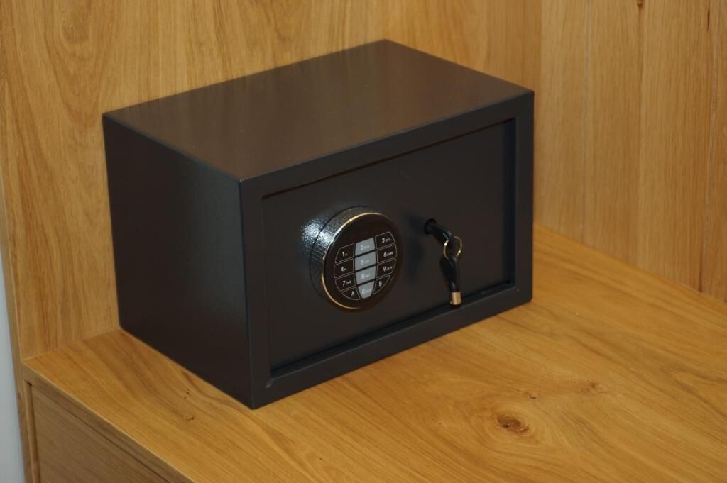 A black safe with a combination dial and keyhole, placed on a wooden surface.
