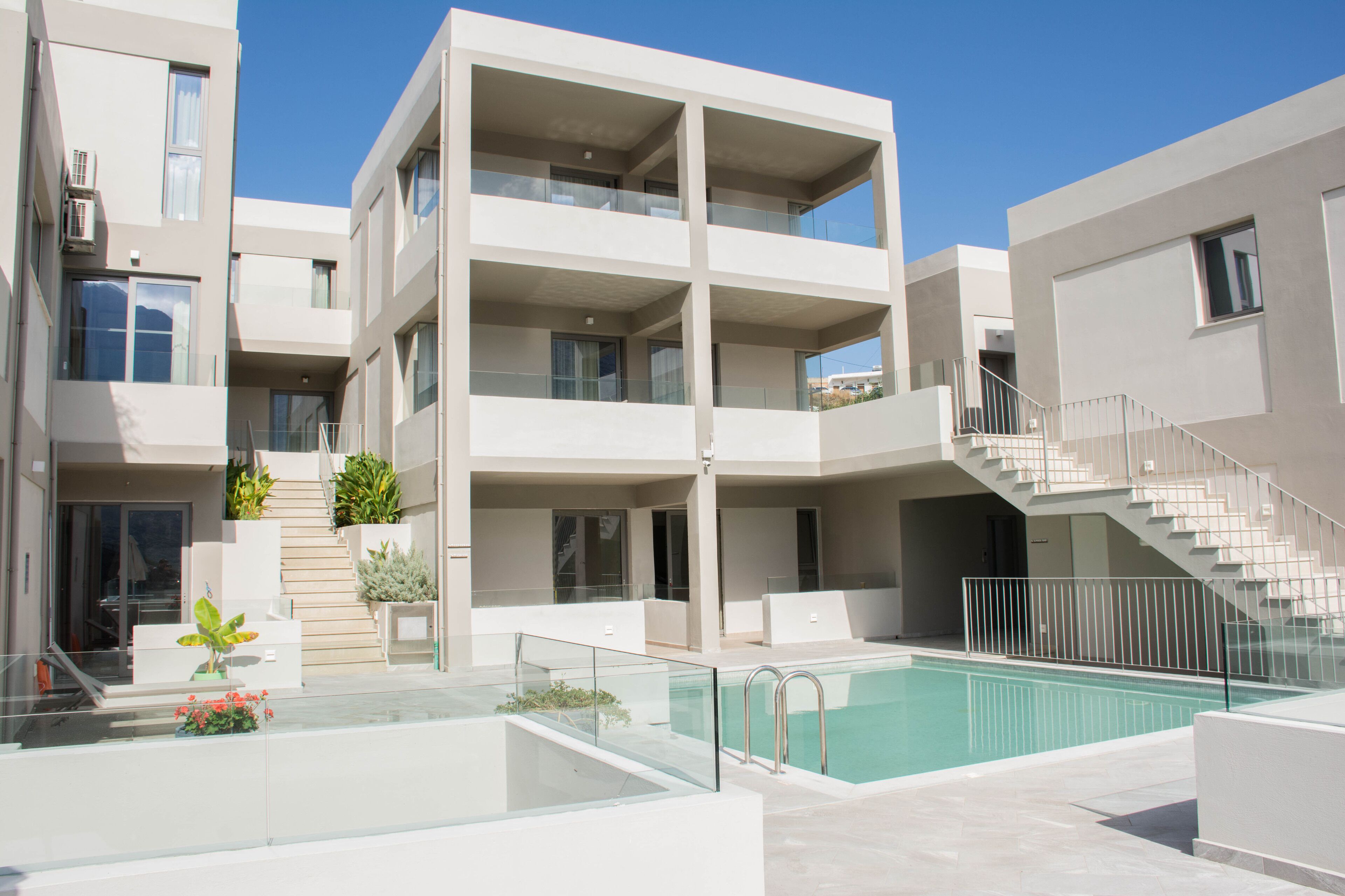 A modern multi-story residential building with a swimming pool, balconies, and a staircase.