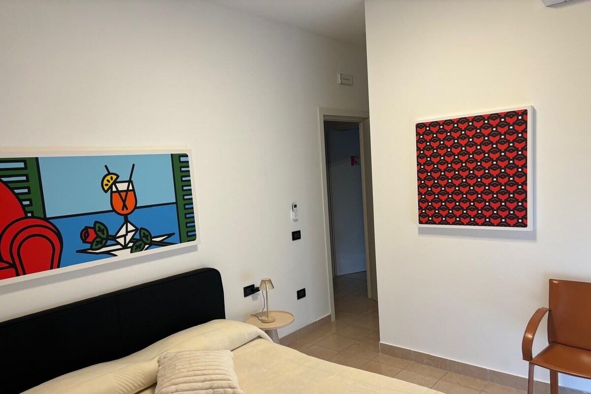 Un dormitorio con una cama, una silla y dos cuadros en la pared.
