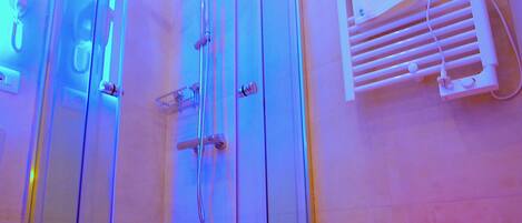 A glass-enclosed shower with a red accent piece, a white towel rack, and a red stool.