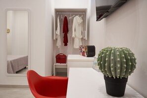 A modern room with a bed, a red chair, a closet with hanging clothes, a small table with a cactus, and a red bag. - Glave Rooms (Termoli)