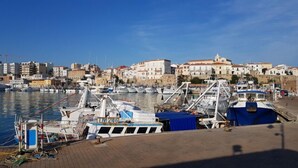 A marina with boats docked, a clear sky, and buildings in the background. - Glave Rooms (Termoli)