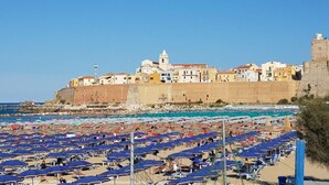 A coastal town with a fortified wall, a beach with numerous umbrellas, and historic buildings. - Glave Rooms (Termoli)