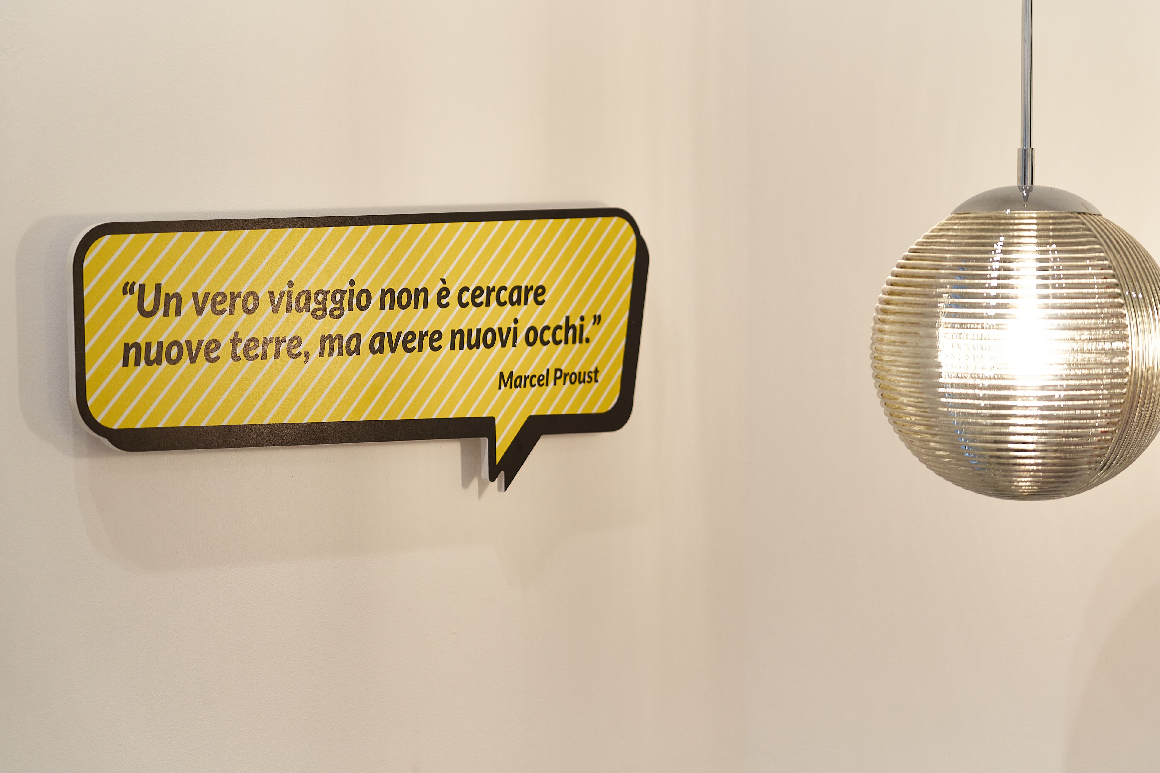 A wall-mounted speech bubble with a quote in Italian.