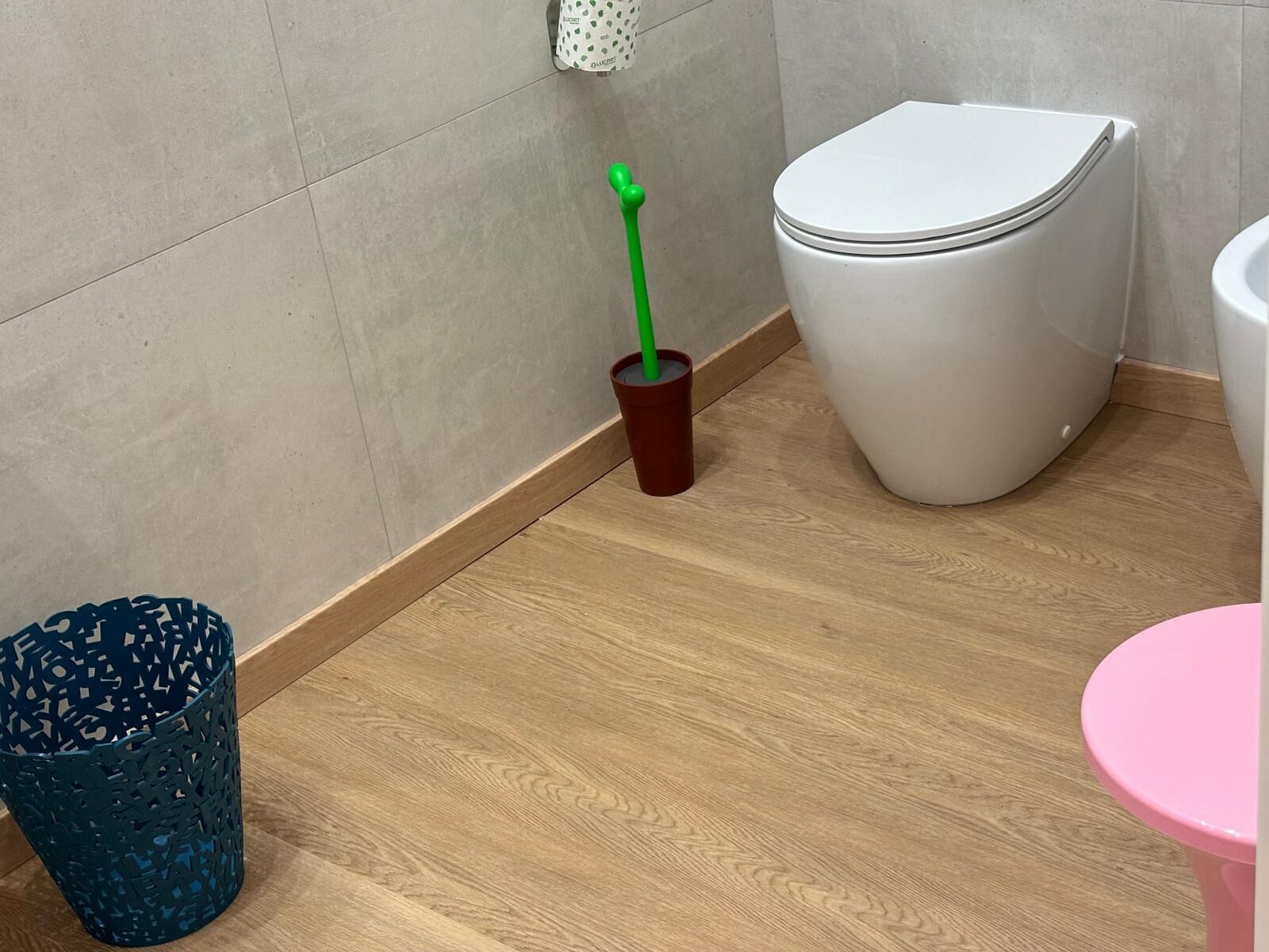 A bathroom with a toilet, a trash bin, and a small table.