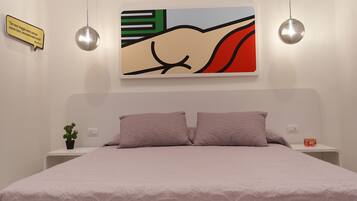 Un dormitorio con una cama, dos mesitas de noche, una planta en maceta y una obra de arte en la pared.