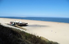 A beach with a small building, likely a beach hut or kiosk, near the water's edge.