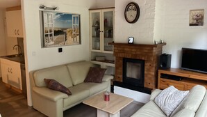 Ein Wohnzimmer mit einer Couch, einem Couchtisch, einem Kamin und einem Fernseher.
