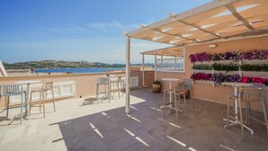 Una terraza con pérgola, mobiliario exterior y una pared cubierta de flores.