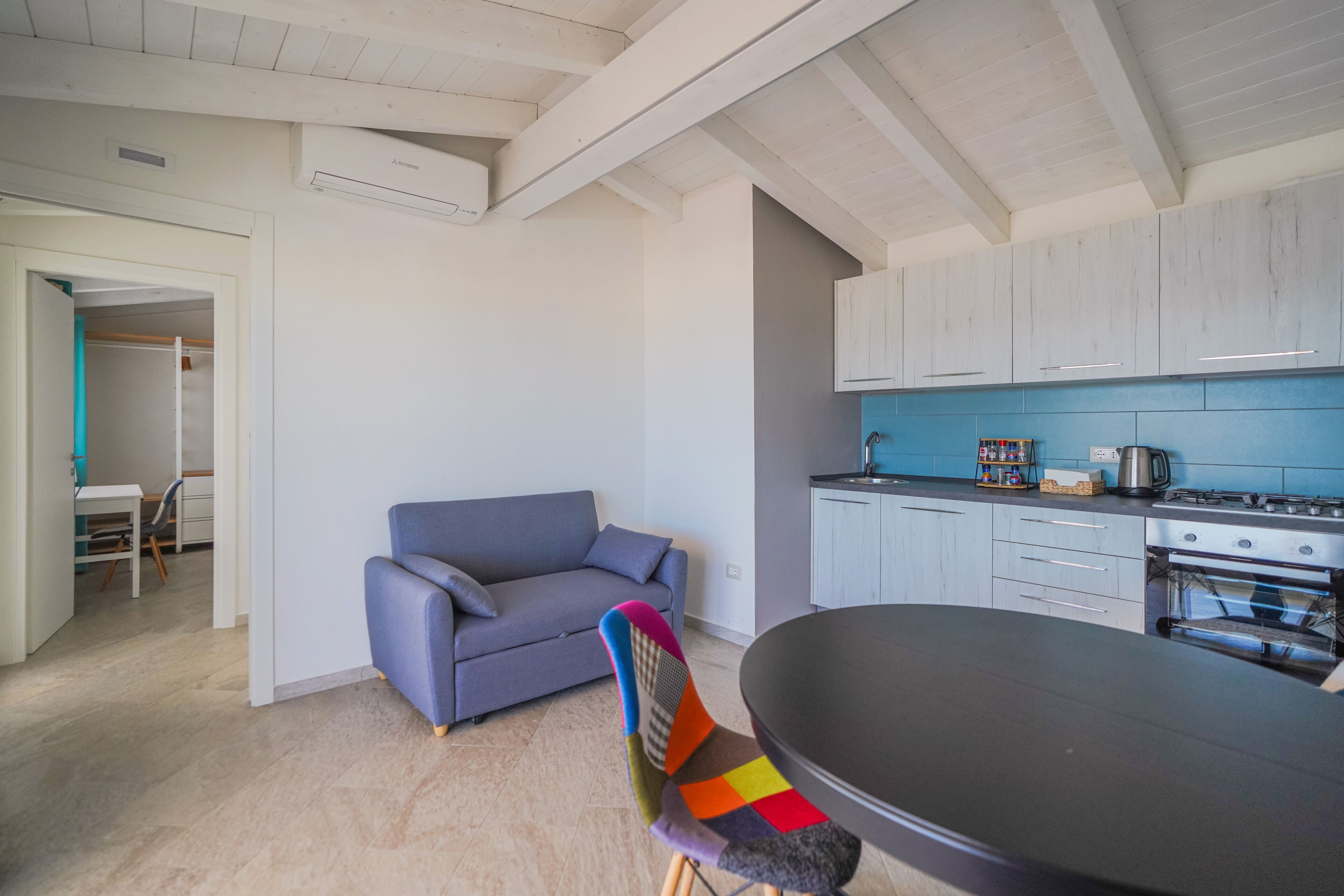 A modern kitchen with white cabinets, a blue countertop, and a dining area with a table and chairs.