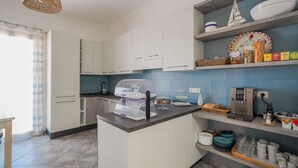 Una cocina moderna con armarios blancos, barra desayunadora y cafetera.