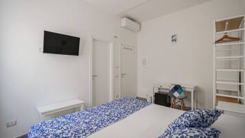 Een slaapkamer met een bed, bureau, stoel, televisie en kledingkast.