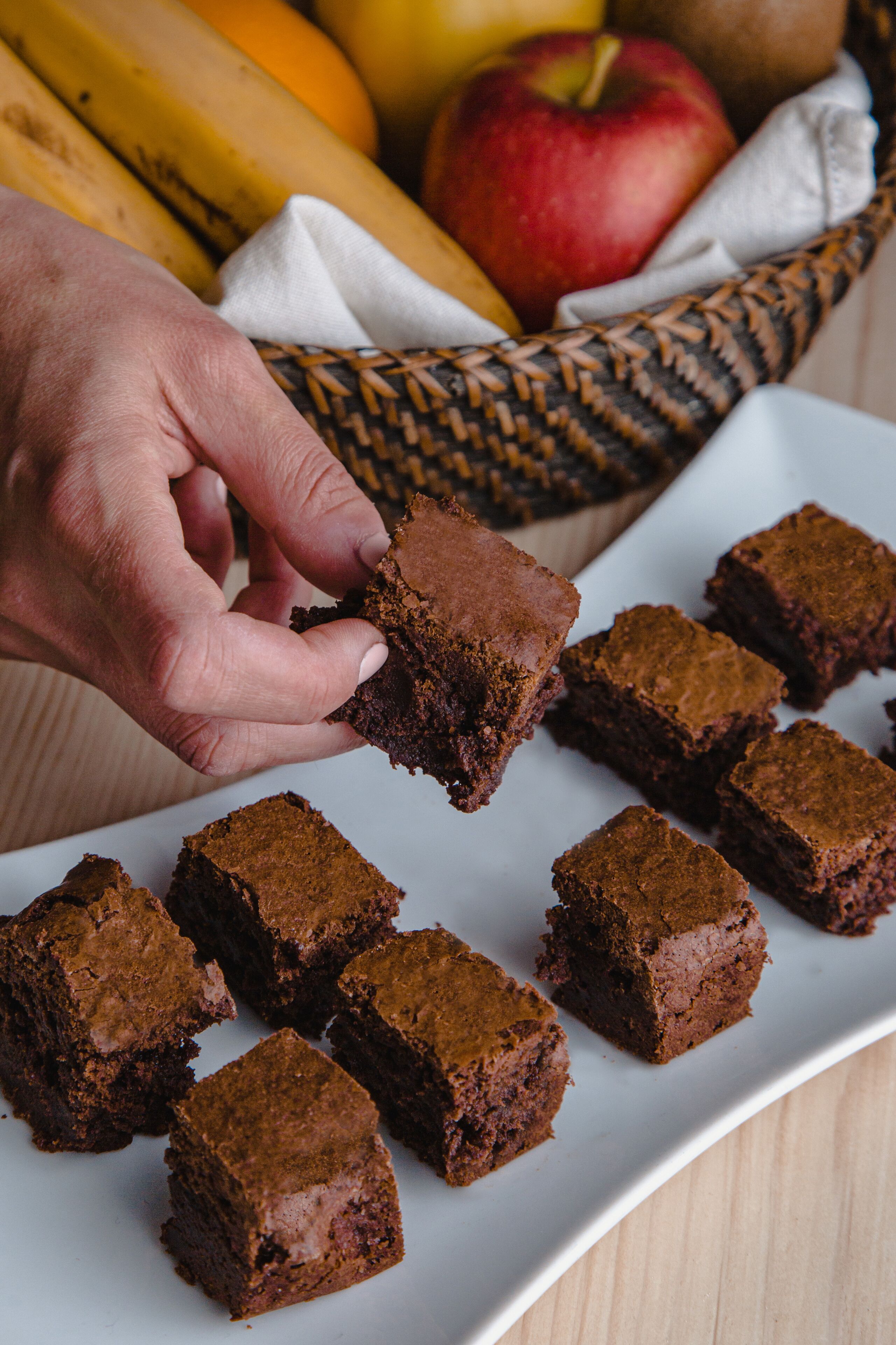 Una mano toma un brownie de un plato lleno de brownies.
