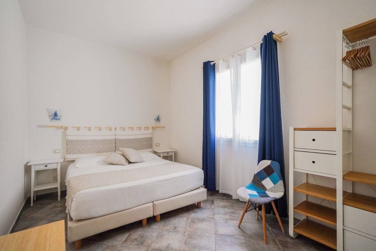 Un dormitorio con cama, una silla, un escritorio y un guardarropa.